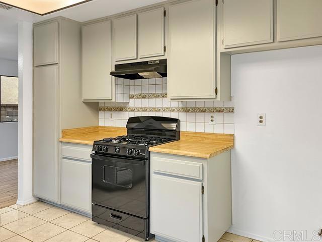 kitchen featuring black range with gas stovetop, tasteful backsplash, and light tile patterned floors