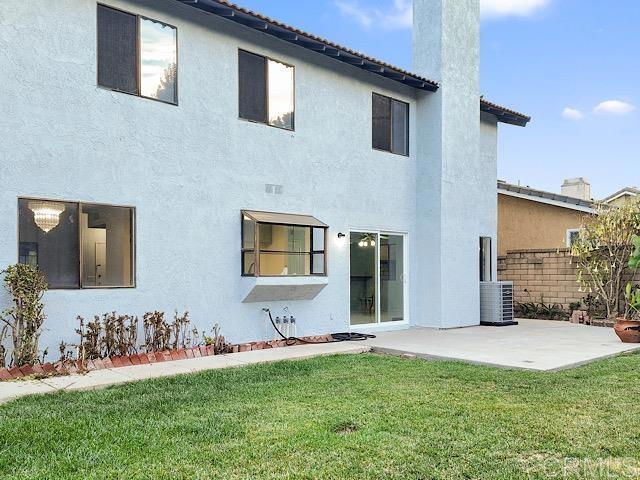 back of property featuring cooling unit, a yard, and a patio