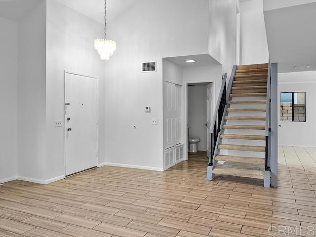 foyer with high vaulted ceiling, light hardwood / wood-style floors, and a notable chandelier