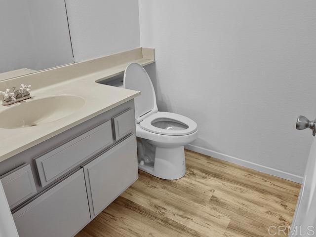 bathroom with wood-type flooring, vanity, and toilet