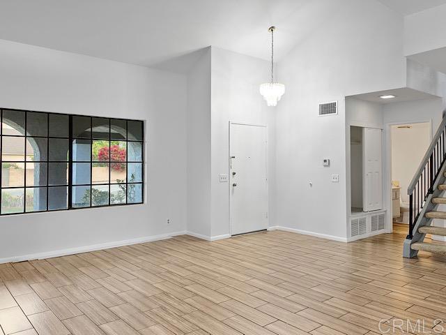 foyer featuring a notable chandelier, light hardwood / wood-style floors, and a towering ceiling