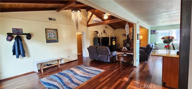 living room with vaulted ceiling with beams, dark hardwood / wood-style flooring, a wood stove, and a wall mounted AC