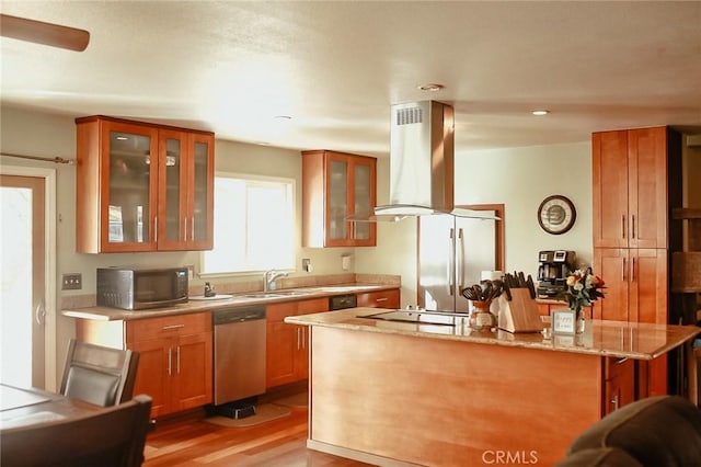 kitchen with a kitchen bar, light stone counters, stainless steel dishwasher, island range hood, and light hardwood / wood-style flooring