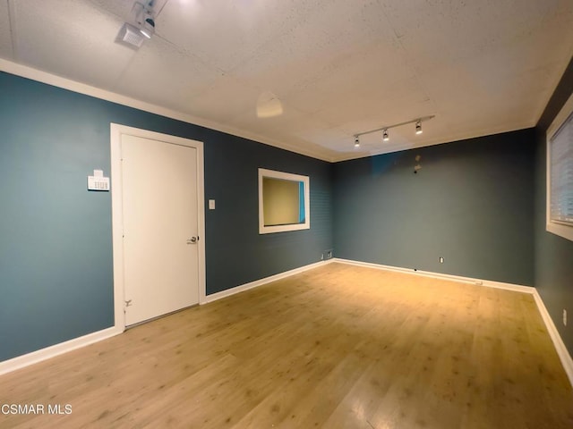 spare room featuring rail lighting and light hardwood / wood-style flooring