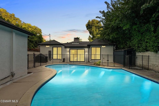 pool at dusk with a patio area