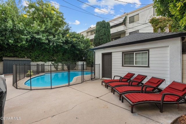 view of swimming pool featuring a shed and a patio area