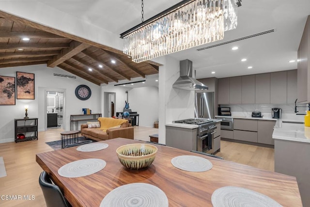 dining space featuring vaulted ceiling with beams, wood ceiling, sink, and light wood-type flooring