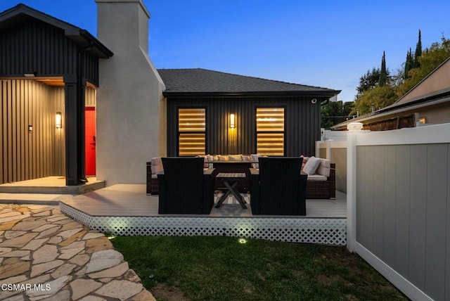 patio terrace at dusk with an outdoor hangout area, a lawn, and a deck