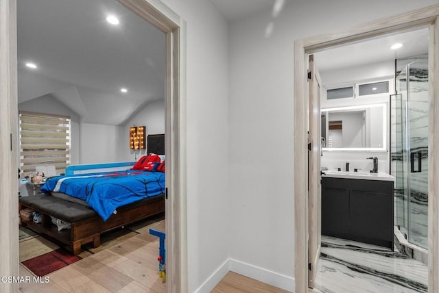 bedroom featuring vaulted ceiling, connected bathroom, and light hardwood / wood-style floors