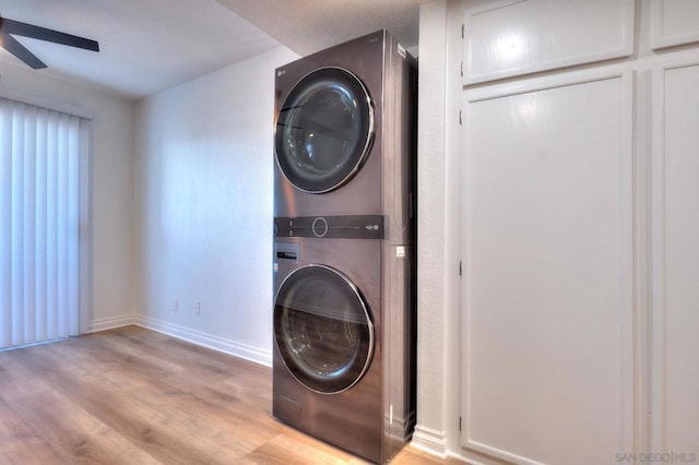 laundry area featuring ceiling fan, stacked washer and dryer, and light wood-type flooring