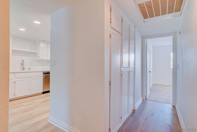 hall with light hardwood / wood-style floors and sink