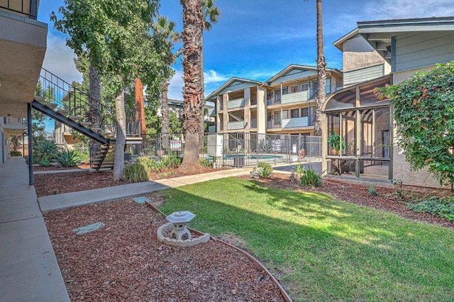 view of yard with a community pool and a sunroom