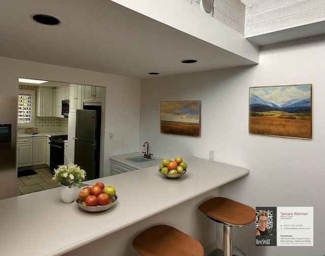 kitchen with sink, kitchen peninsula, a breakfast bar, and black appliances