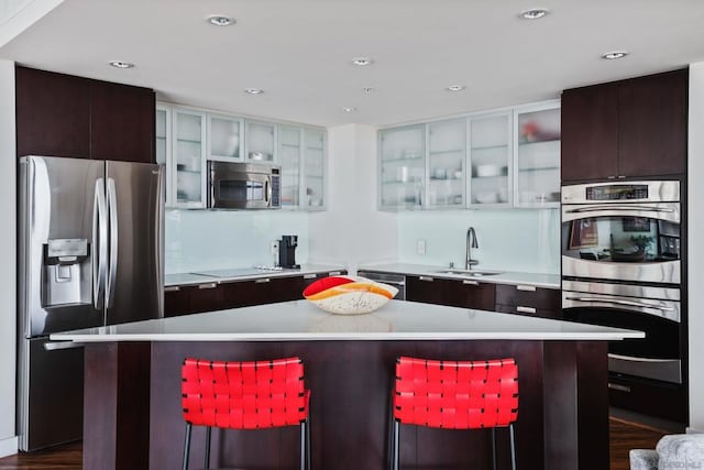 kitchen with sink, dark hardwood / wood-style floors, a kitchen bar, a kitchen island, and appliances with stainless steel finishes