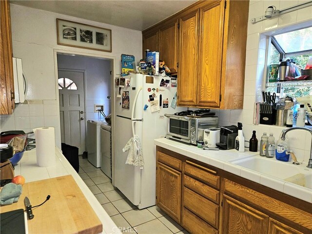 kitchen with sink, independent washer and dryer, backsplash, tile countertops, and white appliances