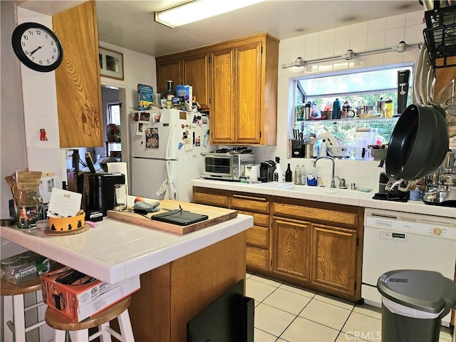 kitchen featuring light tile patterned floors, white appliances, tile countertops, and sink