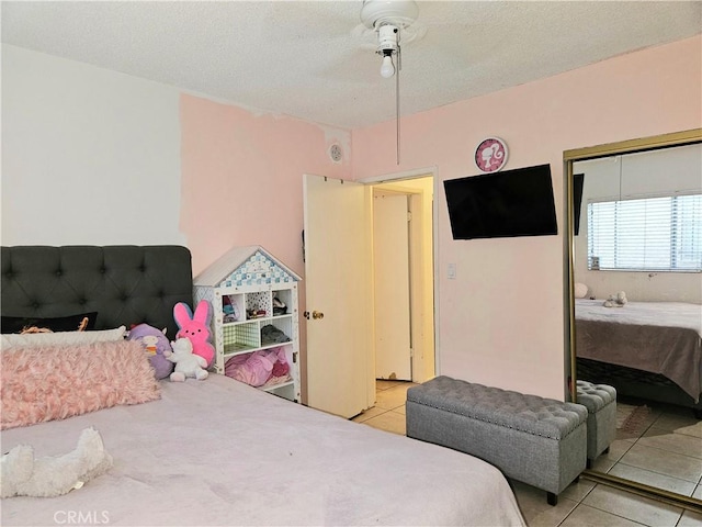 bedroom with ceiling fan, light tile patterned flooring, and a textured ceiling