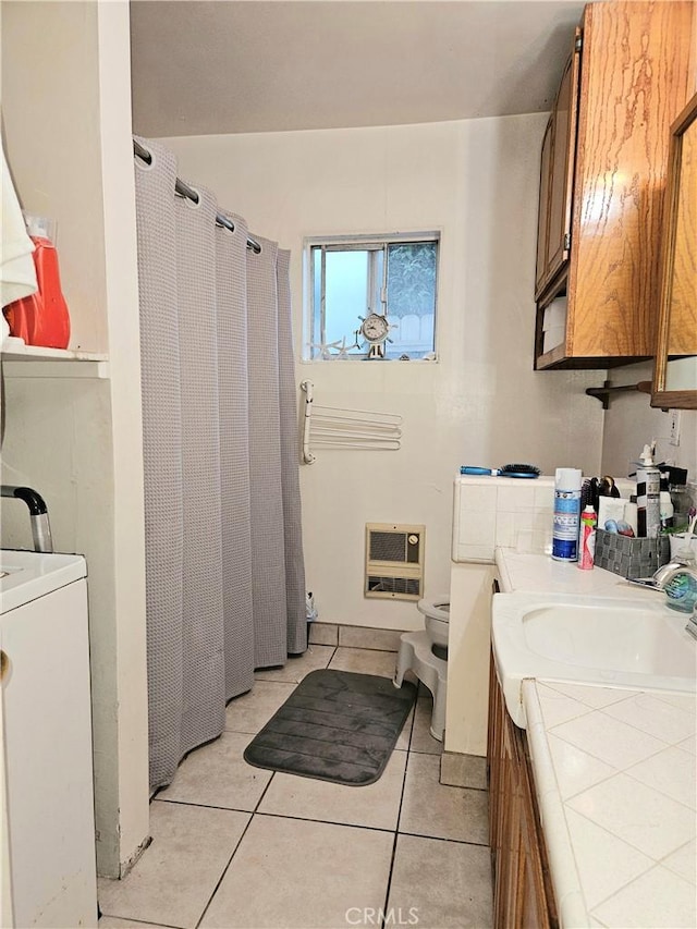 bathroom with vanity, heating unit, tile patterned flooring, washer / dryer, and toilet