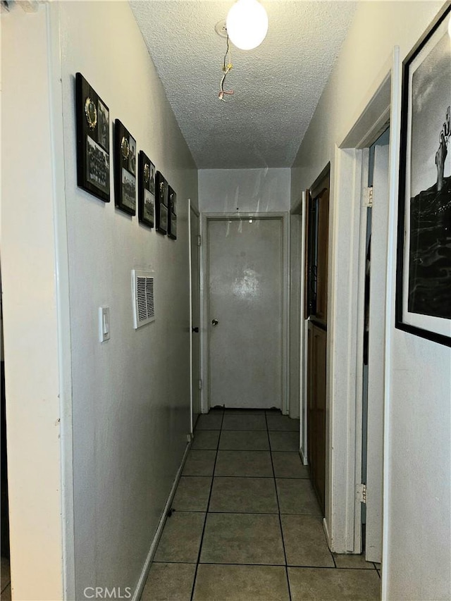 corridor featuring tile patterned floors and a textured ceiling