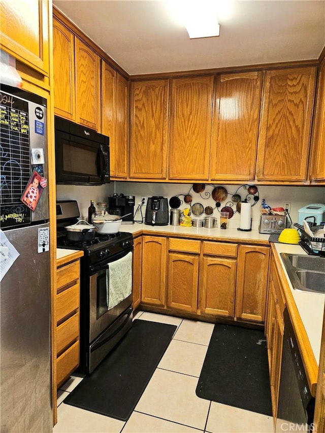 kitchen featuring sink, light tile patterned floors, and black appliances