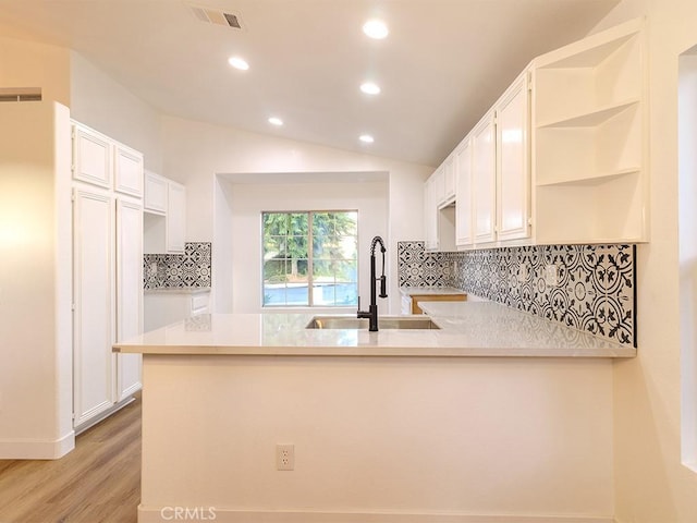 kitchen featuring white cabinetry, light wood-type flooring, kitchen peninsula, and sink