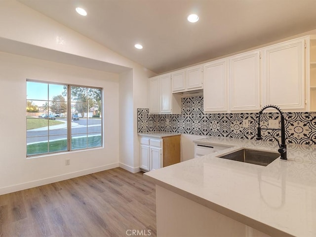 kitchen featuring white cabinets, sink, vaulted ceiling, tasteful backsplash, and light hardwood / wood-style floors