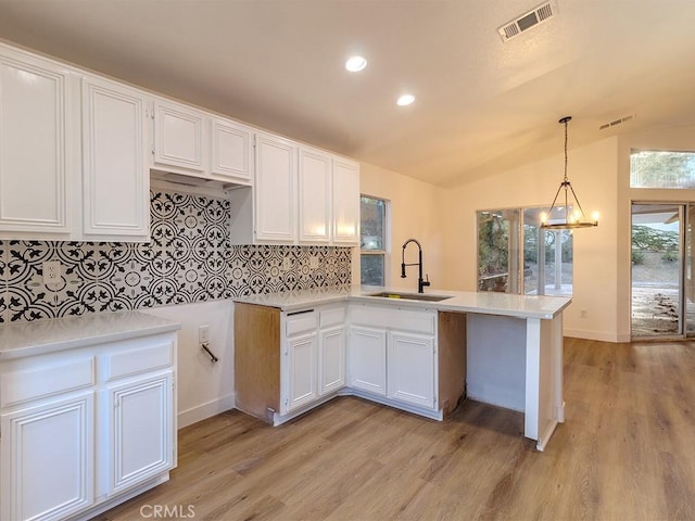 kitchen with lofted ceiling, sink, kitchen peninsula, decorative backsplash, and white cabinetry