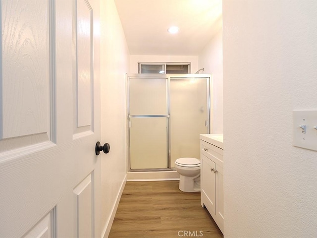 bathroom featuring wood-type flooring, vanity, toilet, and walk in shower