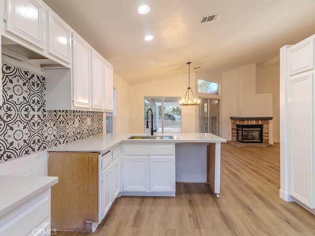 kitchen featuring kitchen peninsula, white cabinets, hanging light fixtures, and lofted ceiling