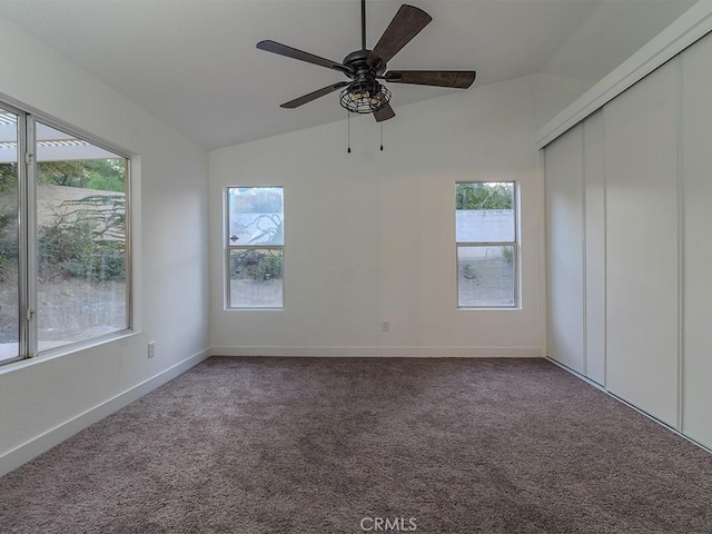 carpeted empty room with ceiling fan, plenty of natural light, and vaulted ceiling