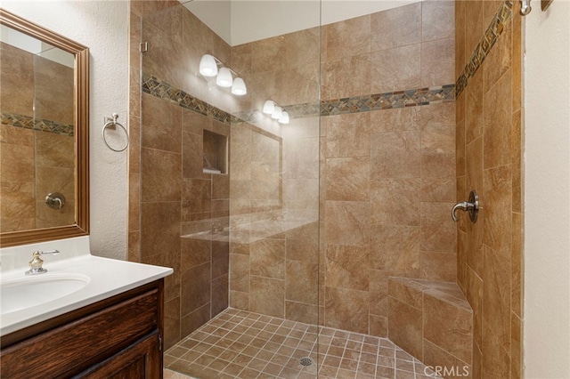 bathroom with a tile shower and vanity