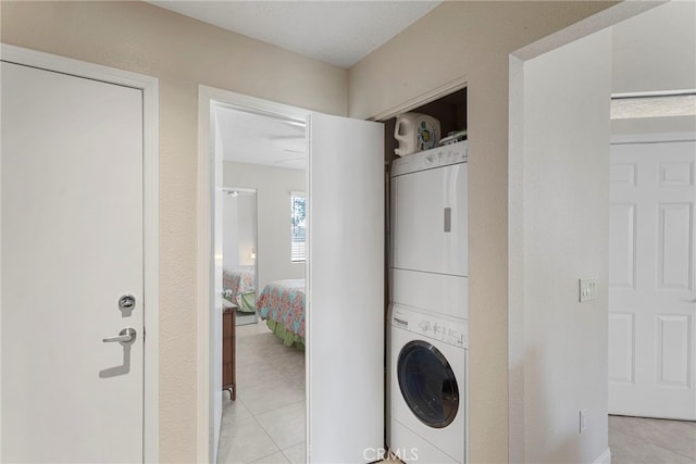 laundry area with light tile patterned floors and stacked washer and dryer