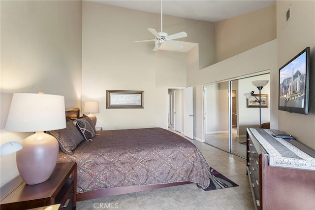 bedroom with ceiling fan, a closet, a towering ceiling, and light tile patterned floors