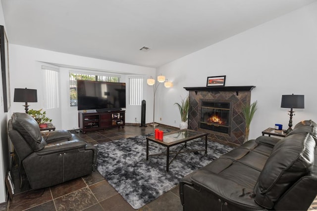 living room with a tile fireplace and lofted ceiling