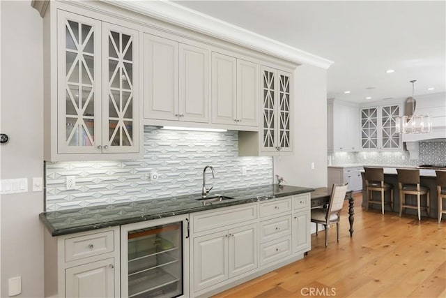 kitchen featuring pendant lighting, light wood-type flooring, beverage cooler, and tasteful backsplash