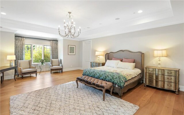 bedroom with a chandelier, a tray ceiling, light hardwood / wood-style flooring, and ornamental molding