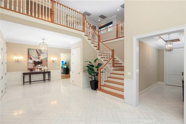 stairway with a towering ceiling, parquet floors, ornamental molding, and a notable chandelier