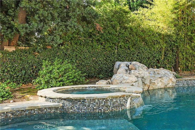 view of swimming pool with pool water feature and an in ground hot tub