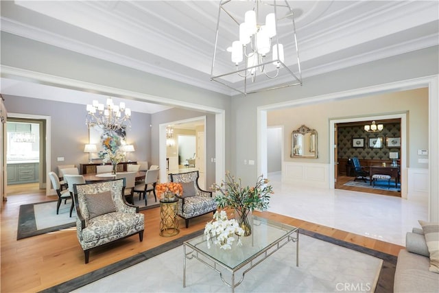 living room with light wood-type flooring, an inviting chandelier, and crown molding