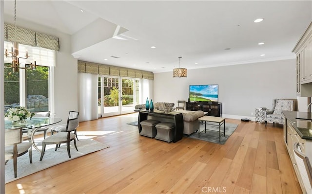 living room with a chandelier, light wood-type flooring, and crown molding