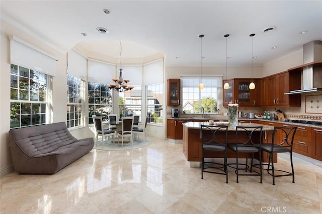 kitchen featuring hanging light fixtures, stainless steel gas cooktop, a kitchen island, and a breakfast bar area