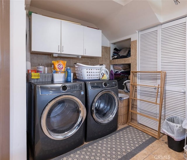 washroom with washing machine and clothes dryer, light tile patterned flooring, and cabinets