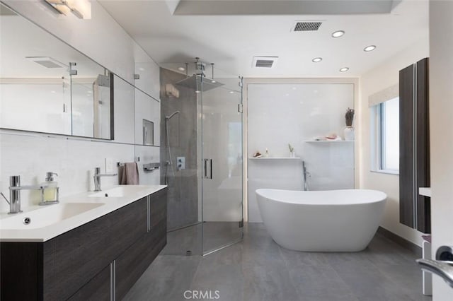 bathroom with shower with separate bathtub, tile walls, vanity, and tasteful backsplash