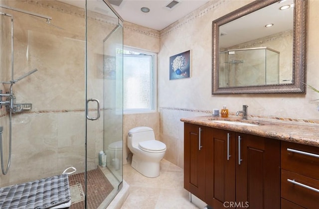 bathroom with a shower with shower door, tile patterned flooring, toilet, tile walls, and vanity