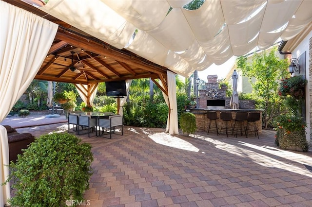 view of patio / terrace with an outdoor bar, ceiling fan, and an outdoor fireplace