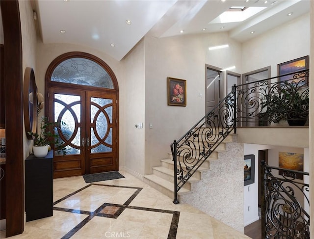 foyer featuring a towering ceiling, french doors, and a skylight