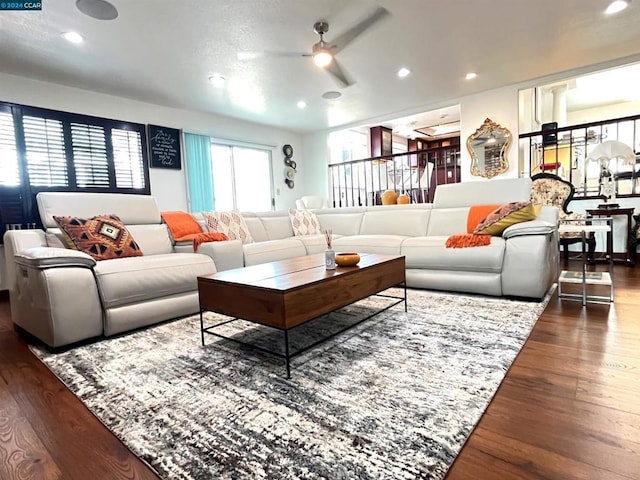 living room featuring ceiling fan and dark wood-type flooring