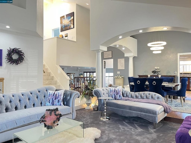 carpeted living room featuring high vaulted ceiling, a notable chandelier, and ornate columns