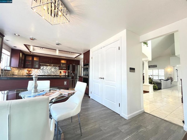 dining area featuring a raised ceiling, dark hardwood / wood-style floors, sink, and decorative columns