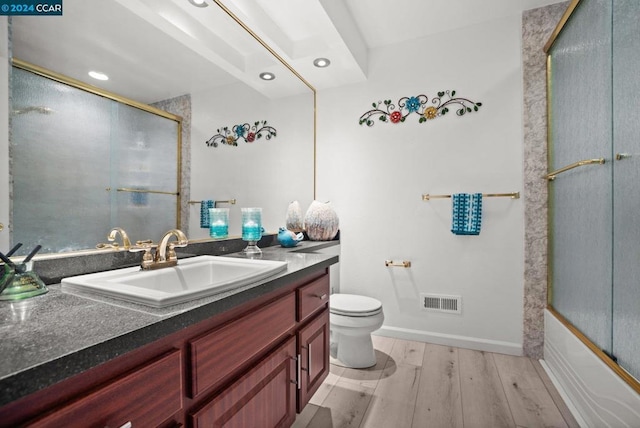 full bathroom featuring toilet, combined bath / shower with glass door, and vanity